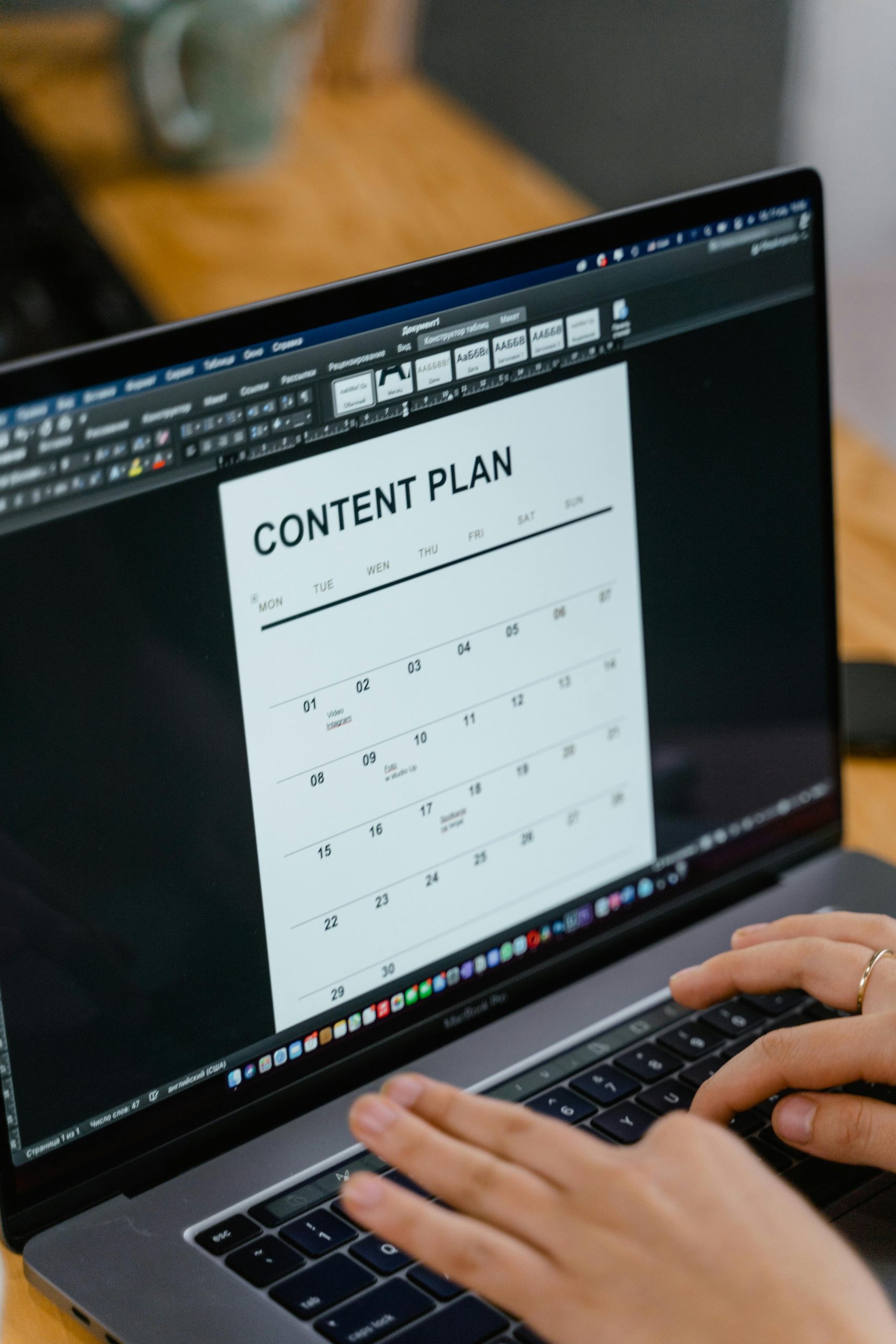 Close-up of hands typing on a laptop displaying a content plan document, ideal for business or marketing content.